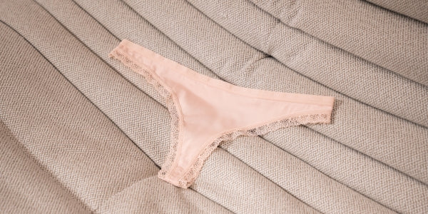 Vee gstring and white singlet lying on a bed